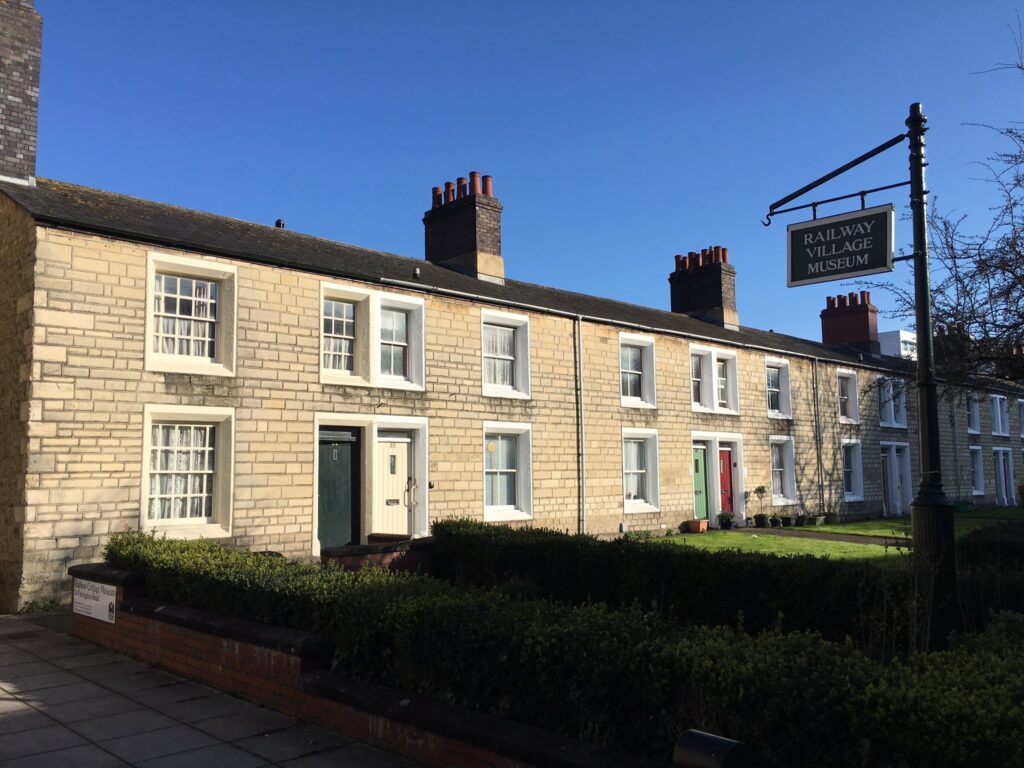 34 Faringdon Road sits below blue skies. The sandstone reflects the golden sun onto the green gardens in front.