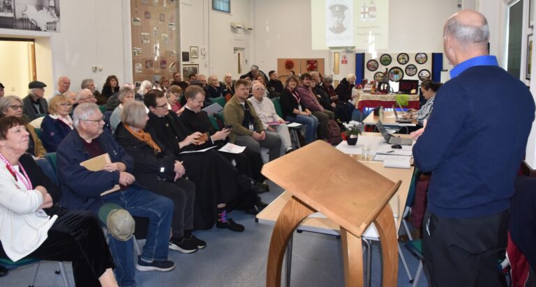 A large audience faces the presenter.