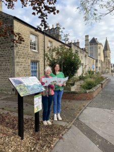 Allie and Hannah follow the Children's Heritage Story Trail in Swindon's Historic Railway Village. They stand at one of the WORKS trail signs, located in front of the Central Community Centre.